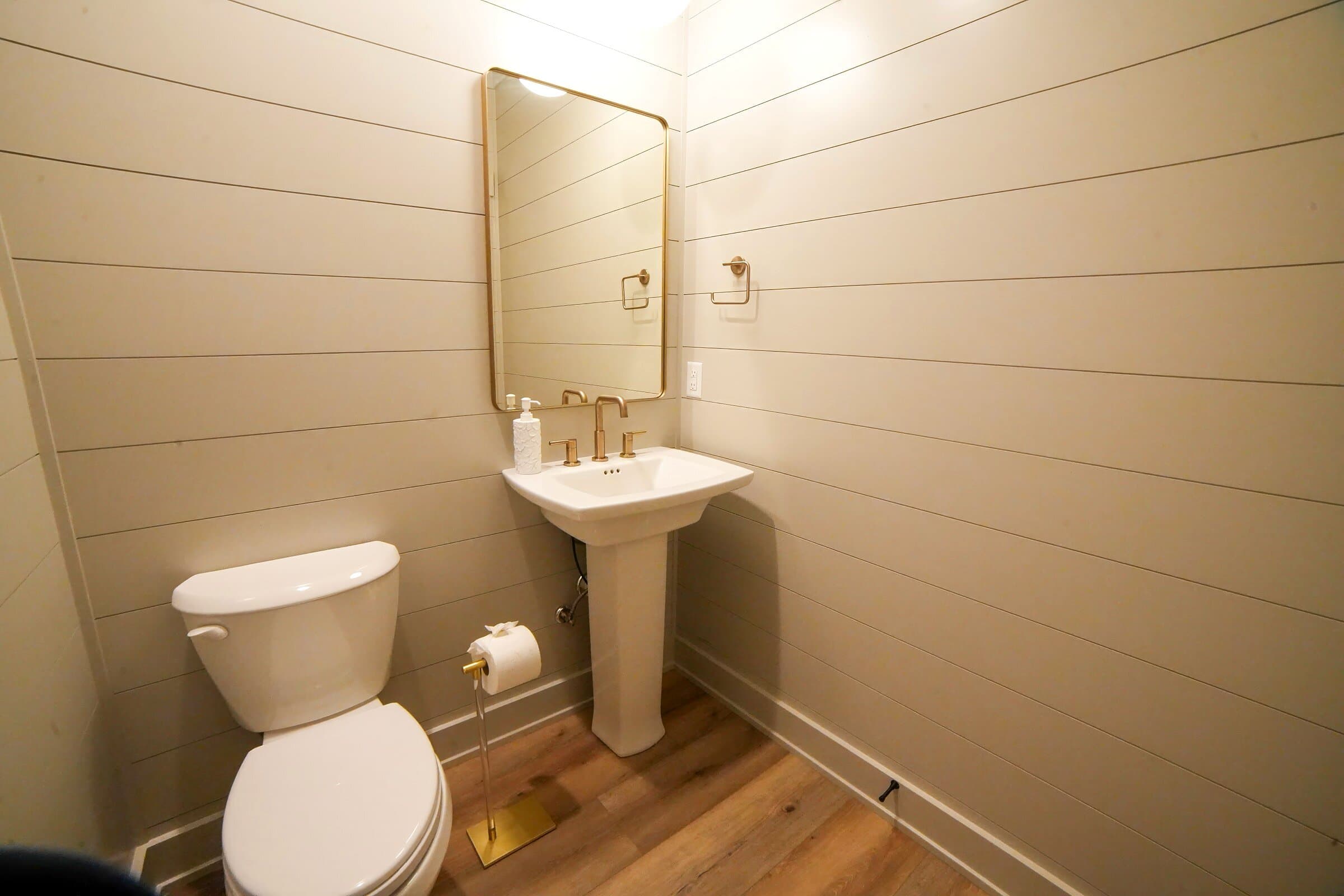 Powder room — Shiplap walls, brass mirror, pedestal sink