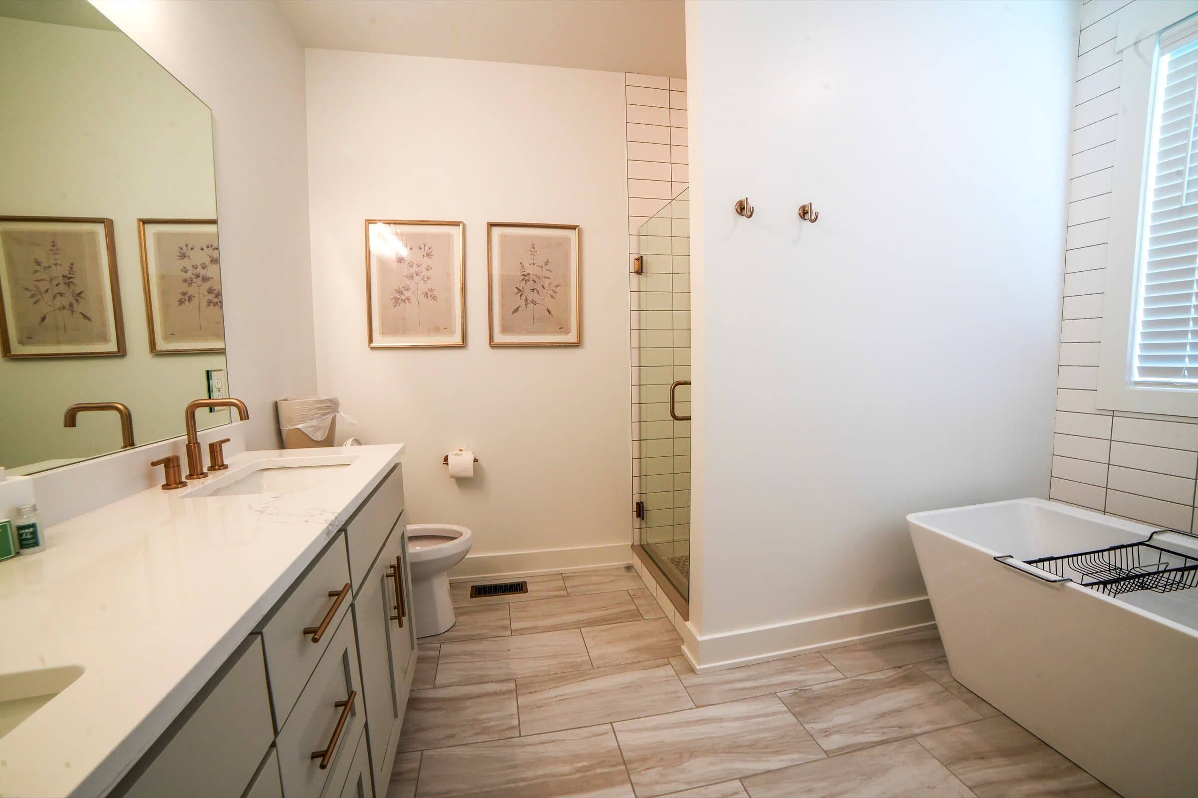 Primary en suite — Walk-in herringbone-tile shower, freestanding tub, double vanity, brass fixtures